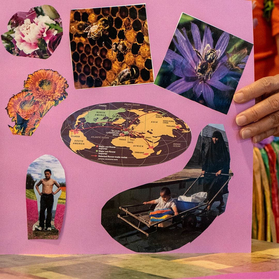 A person with orange shirt is holding a collage art on a bright pink paper. The paper shape is square and there are seven cut out images on it. From left to right; a picture of pink flower, a close-up of a beehive, a close up of a purple flower with a bee on top of it, two sunflowers, a world map, a cut-out picture of a shirtless man on another picture of a colorful flower field and a picture of a woman in an all-black outfit pushing a cart with a baby in it.