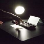A hand in the dark manipulating an 8-channel mixer.