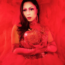 Performance photo of Maiden China in a red costume dress, against a red background.