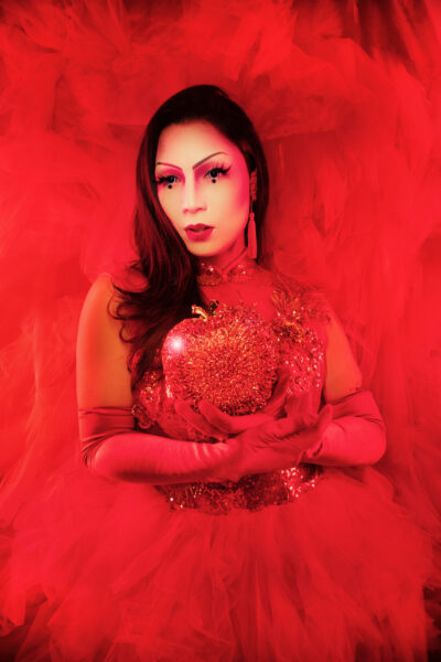 Performance photo of Maiden China in a red costume dress, against a red background.