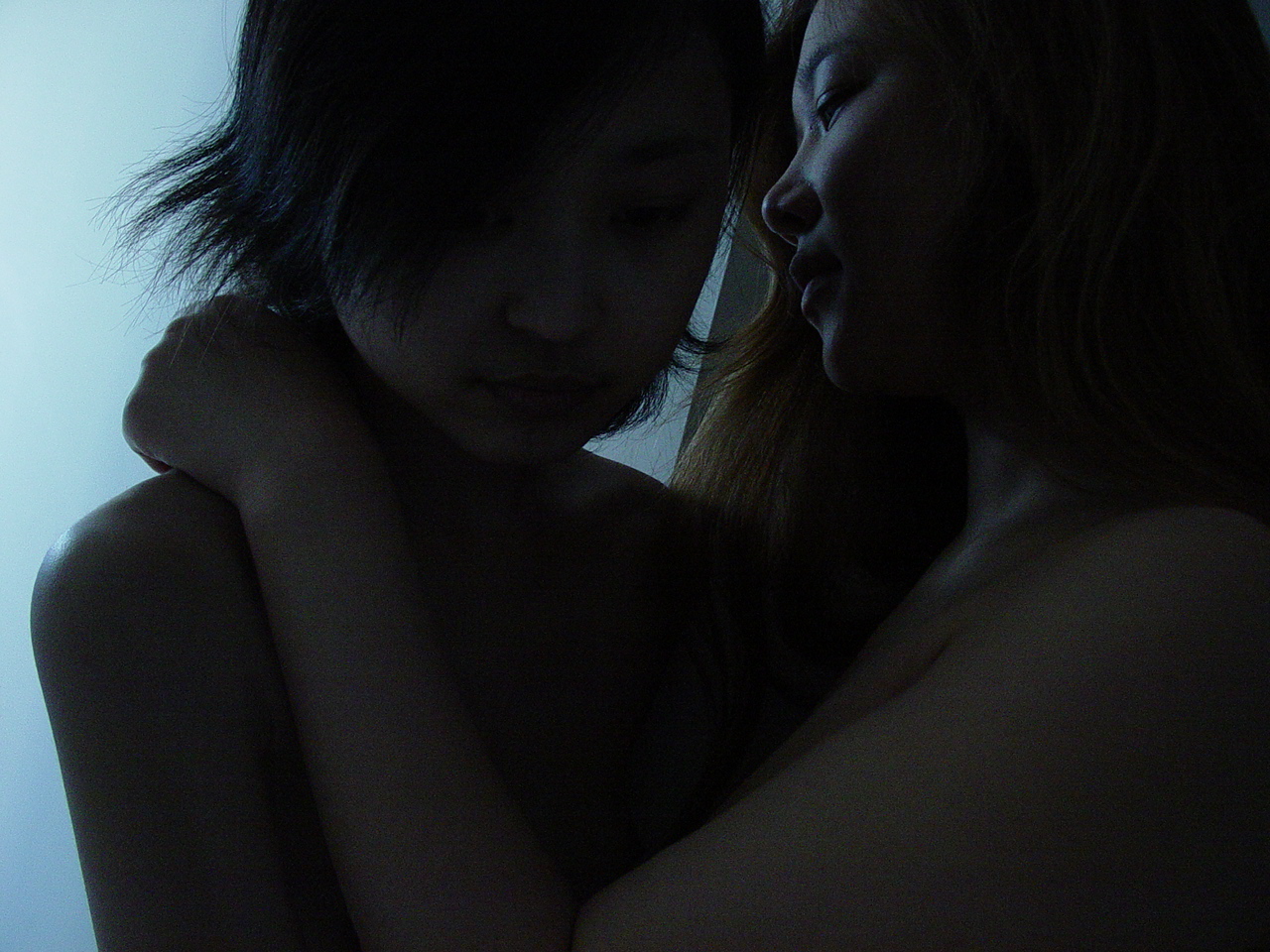 Still from sisters. A close up, showing two people in shadow, embracing.
